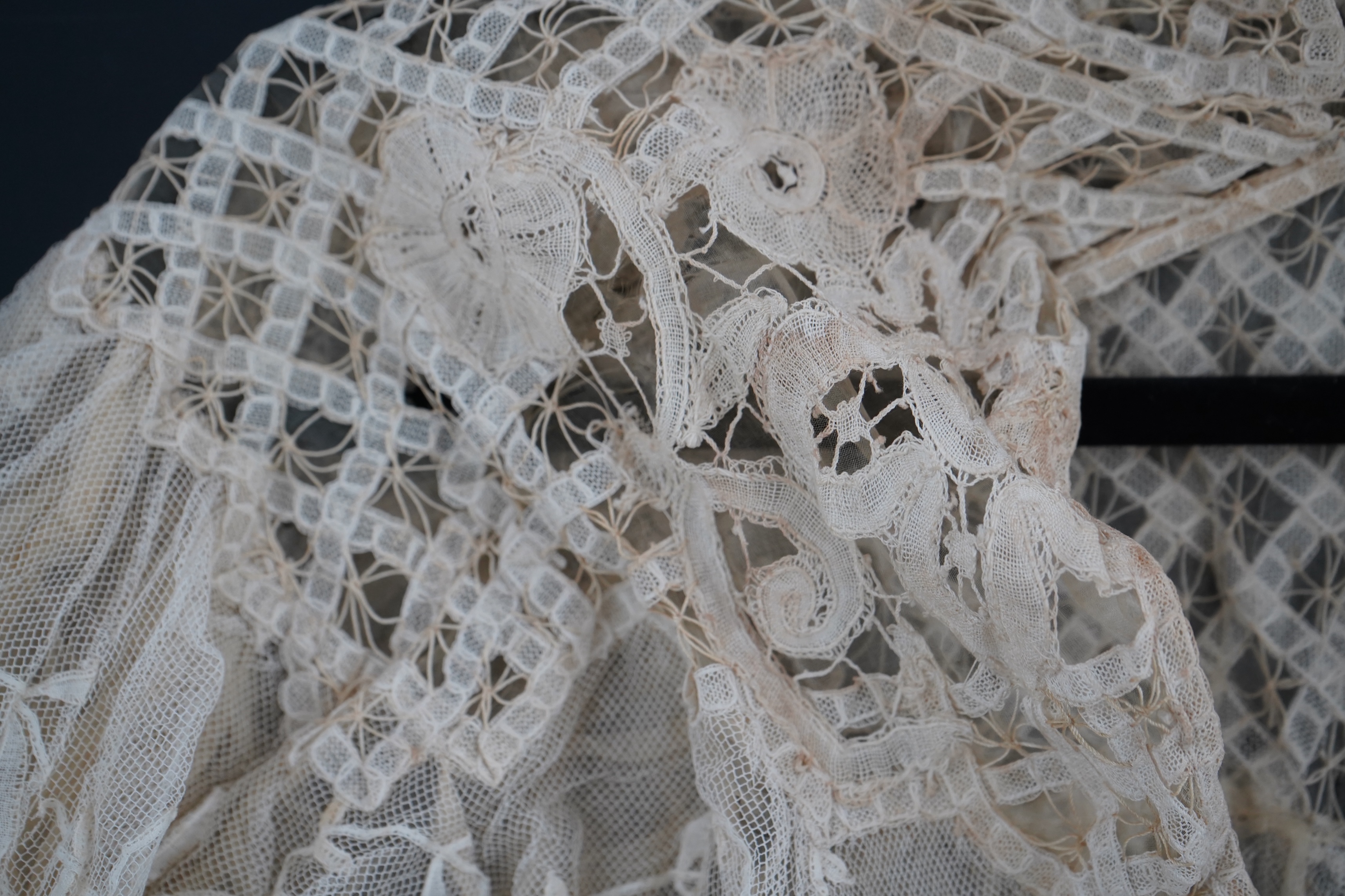 An Edwardian high collared cream tape lace wedding over blouse, made with a deep net frill and cream chiffon rose detail hanging from lower edge, top of collar to rose detail at the front 46cm. Condition - fine silk chif